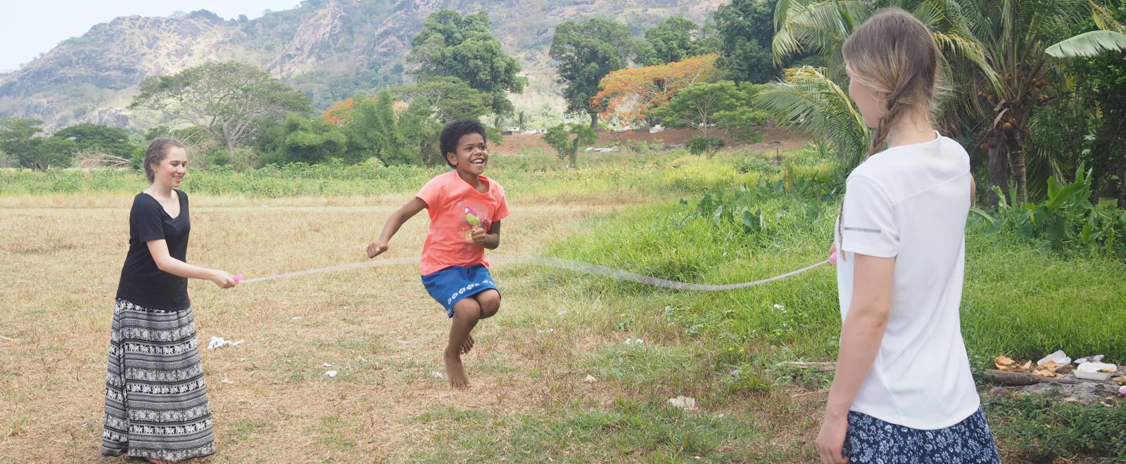 Two sisters playing with a skipping rope with a child on the Projects Abroad Childcare Programme in Fiji